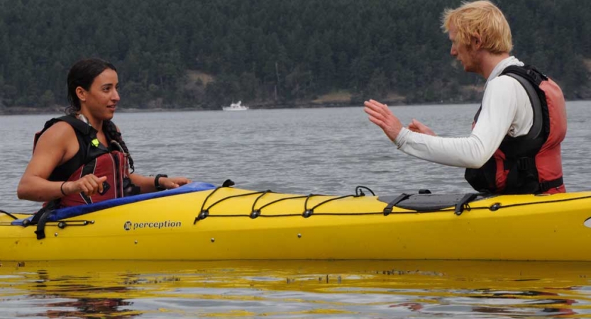 an instructor gives direction to a student in a kayak on an outward bound trip